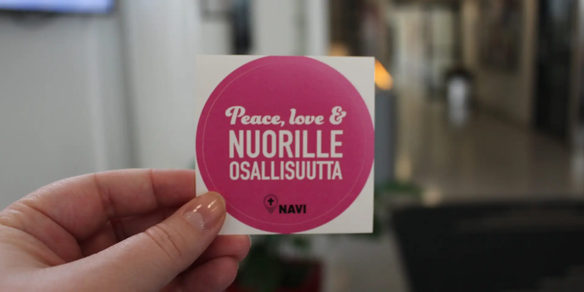 Tarra, jossa lukee "Peace, love & Nuorille osallisuutta". Tarran alareunassa nuorten aikuisten vaikuttamisryhmä Navin logo.